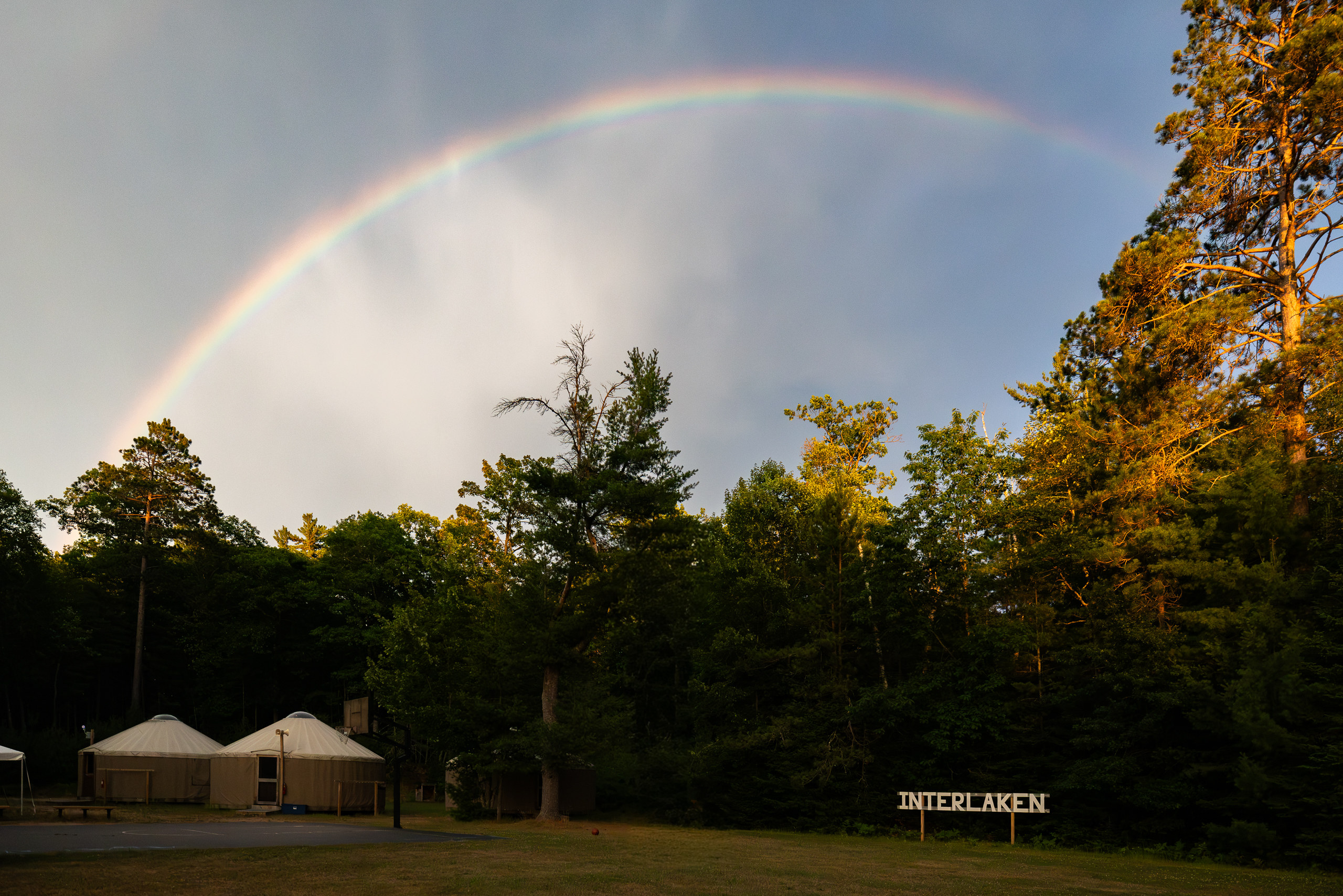 A full rainbow over camp, the camp's name beneath it